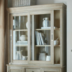Upper dresser-top cabinet styled with books and white and blue-patterned ceramics, shown above an adjoining base unit beside a curtain.