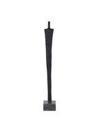 Full front view of a slender black abstract figure sculpture on a grey square base against white.