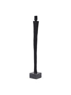Angled view of the black figure sculpture showing its block-shaped head, narrow body and square base.