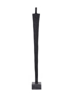 Rear view of the elongated black figure sculpture with a textured tapering body and contrasting grey base.