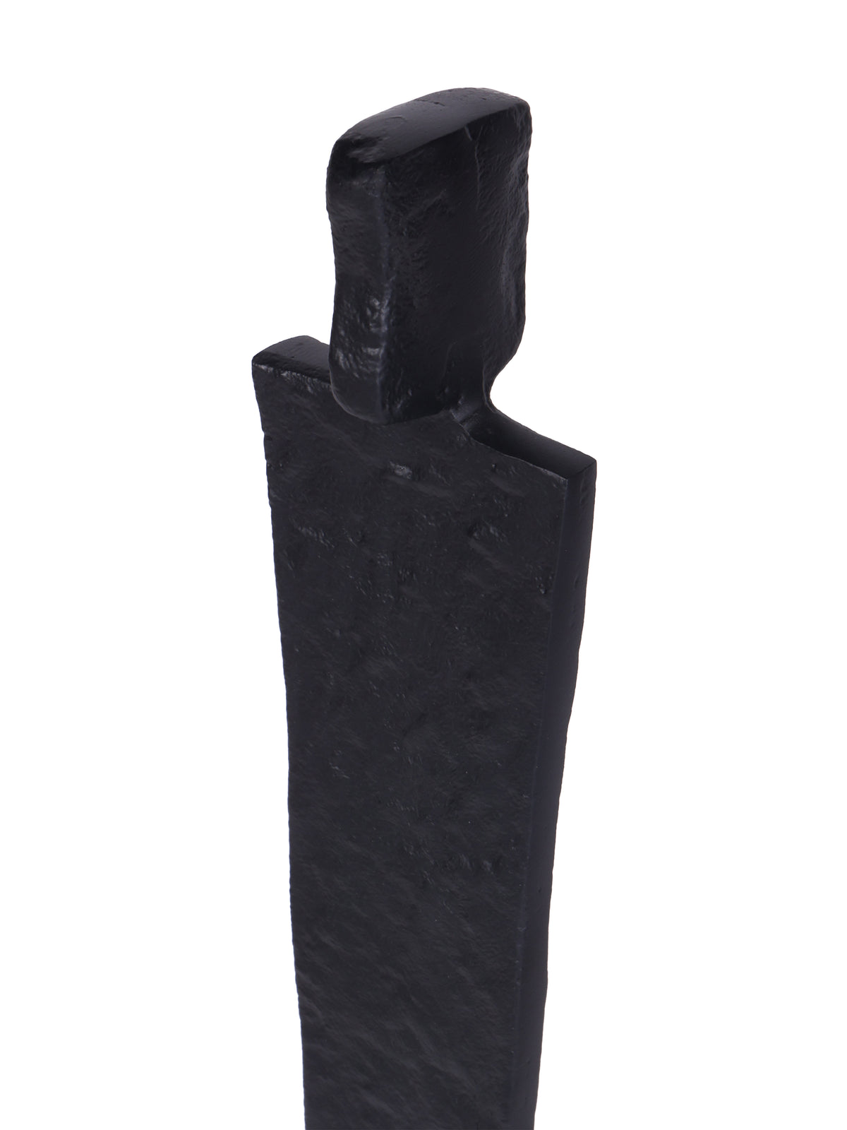 Close-up of the sculpture's rectangular head and broad shoulders, showing the uneven texture of the black finish.