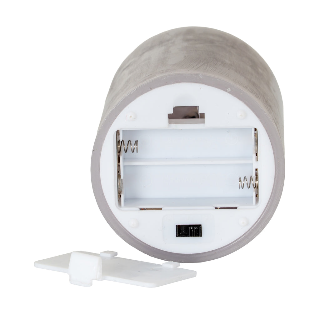 Underside of the grey candle showing two empty battery channels with springs, a black slider and a detached white compartment lid.