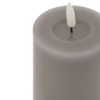 Close-up of the grey candle's broad circular rim and recessed centre, with a white flame insert on a short black stem.