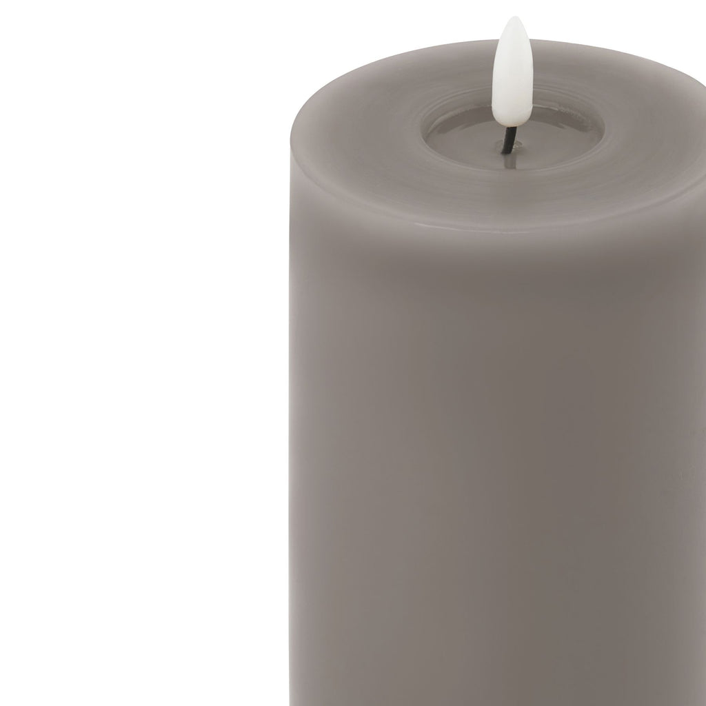 Close-up of the grey candle's circular recessed top, showing the white flame-shaped insert on a short black stem.