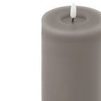 Close-up of the grey candle's circular recessed top, showing the white flame-shaped insert on a short black stem.