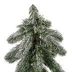 Close-up of the decorative tree's pointed top and tiered green needles with uneven white flocking, showing the brown trunk between the branches.