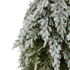 Detail of fine green foliage beneath thick white flocking along the tree's cascading branches.