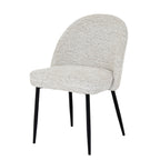 Three-quarter front view of a pale textured armless dining chair with a rounded back, thick seat and four slim black legs.