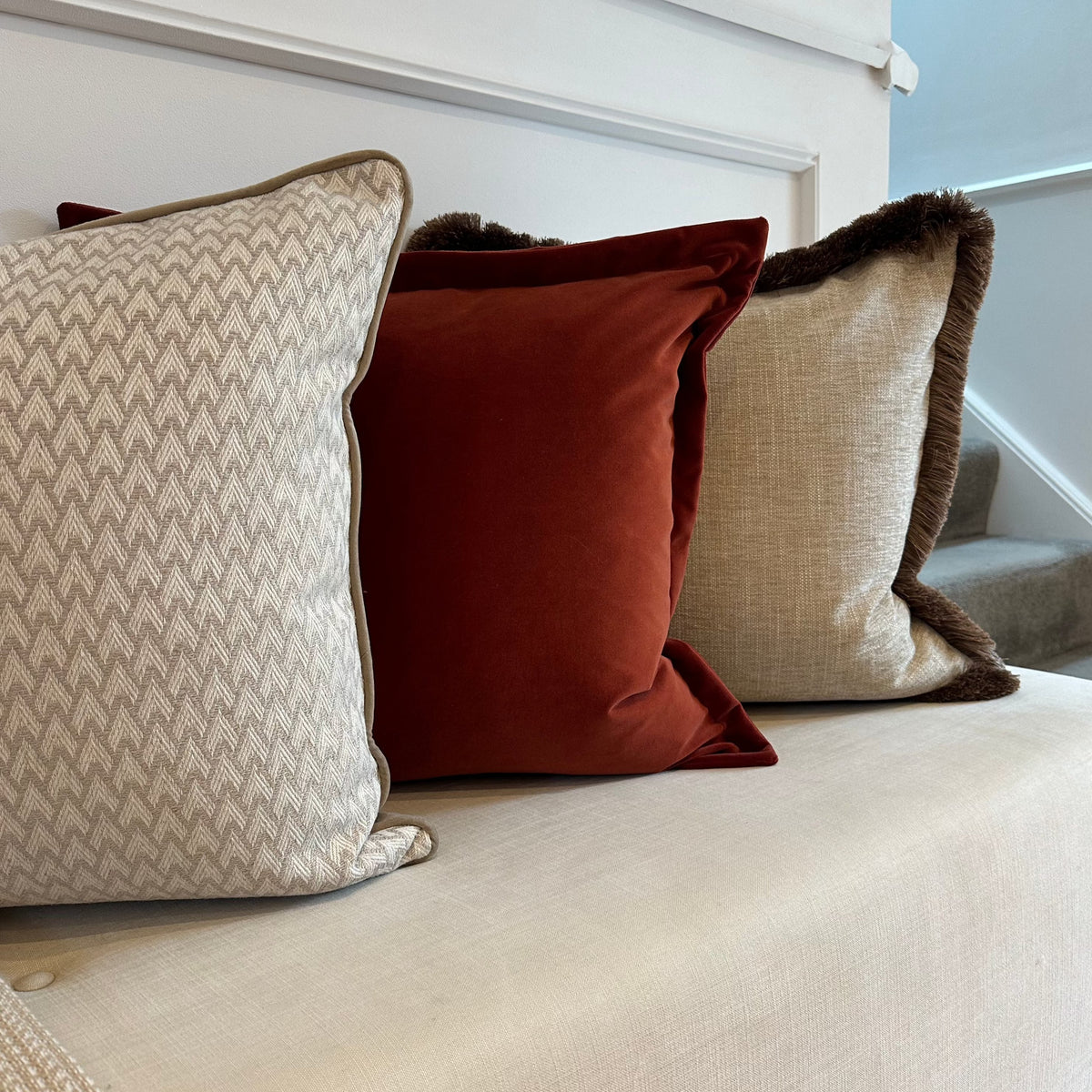 Sorelle Cushion with brown fringe styled on a sofa with rust and neutral cushions