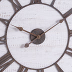 Close-up of the clock's mottled rust-brown hands and central disc against the distressed whitewashed face, with parts of the Roman numeral ring visible.