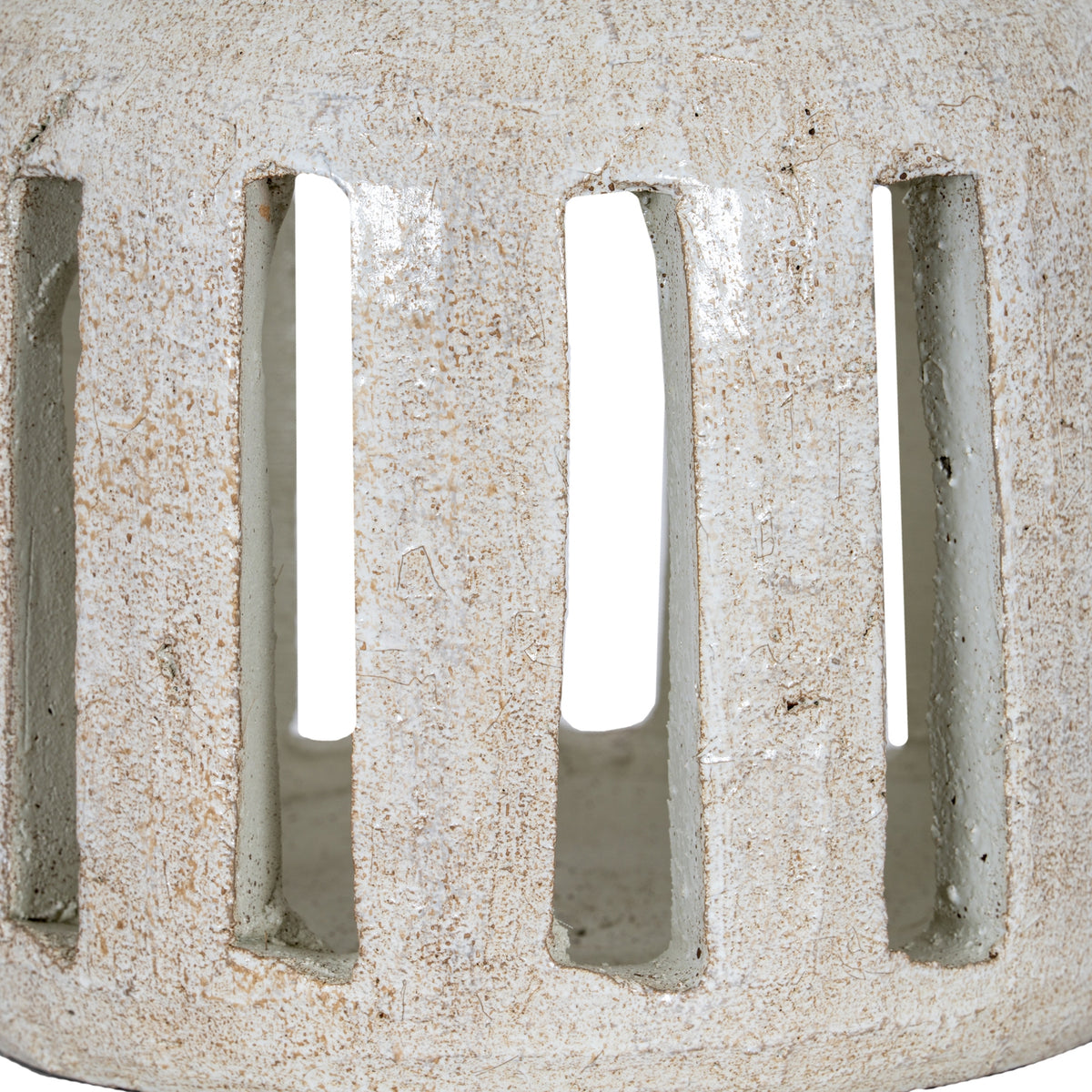 Close-up of the candle holder's tall rectangular openings and rounded lower edge, with brown flecks and fine irregular lines across the white surface.