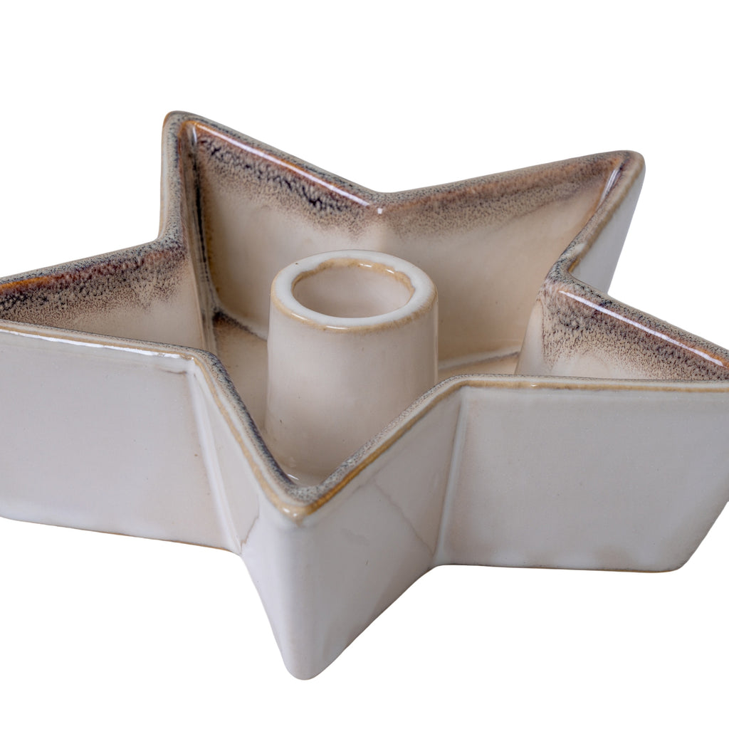 Angled close-up of the star candle holder showing its cylindrical central socket, glossy upturned sides and brown-grey speckling along amber-toned edges.