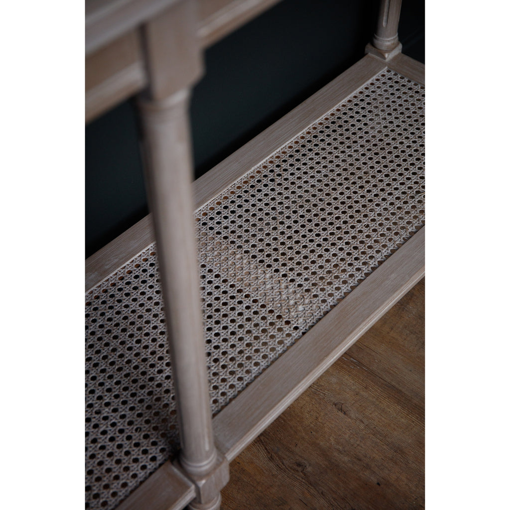 Angled close-up of the lower shelf's open woven pattern and grey border, with a slender leg in the foreground.