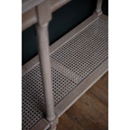 Angled close-up of the lower shelf's open woven pattern and grey border, with a slender leg in the foreground.