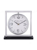 Front view of a mantel clock with a white round dial suspended inside a silver square frame on a black base.