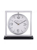 Front view of a mantel clock with a white round dial suspended inside a silver square frame on a black base.