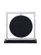 Rear view of the mantel clock with a black circular back inside the silver square frame.