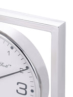 Close-up of the polished upper corner of the square clock frame beside the curved dial rim.