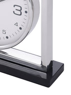 Detail of the clock's lower frame corner and polished black granite base beneath the white dial.