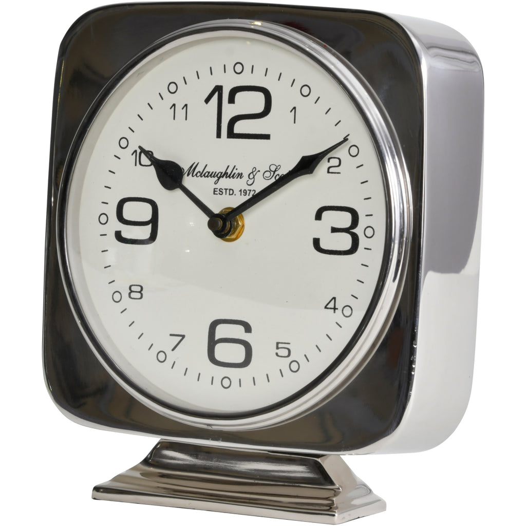 Angled front view of a silver square mantel clock with a pale round dial, black numerals and a stepped pedestal base.