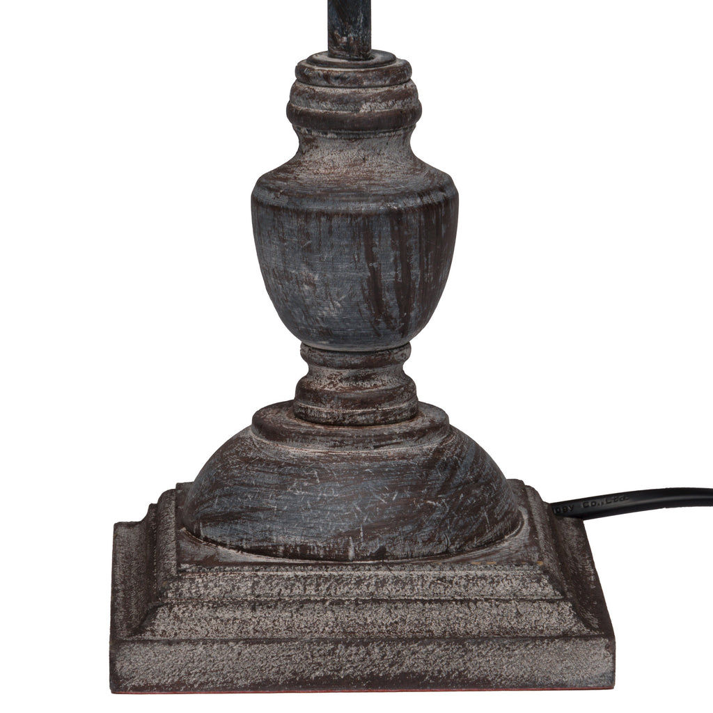Close view of the lamp's curved grey-washed base and stepped square plinth, with a black cord extending to the right.