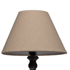 Close view of the pale tapered lampshade's fine surface texture, with the dark curved detail beneath its lower edge.