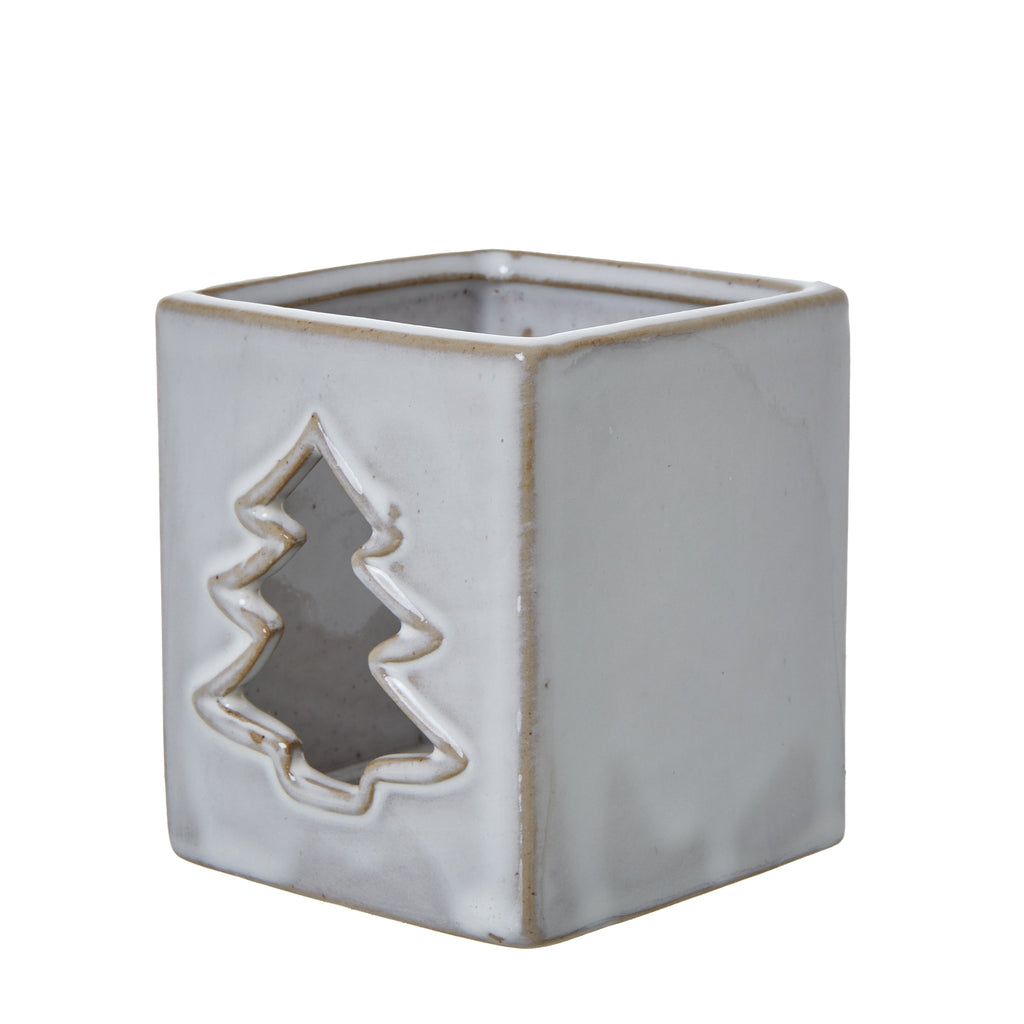 Angled view of the ceramic candle holder showing the tree aperture beside a plain side and lightly speckled glossy finish.