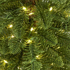 Close-up of green needle-like artificial foliage with warm lights and fine green wires running between the branches.