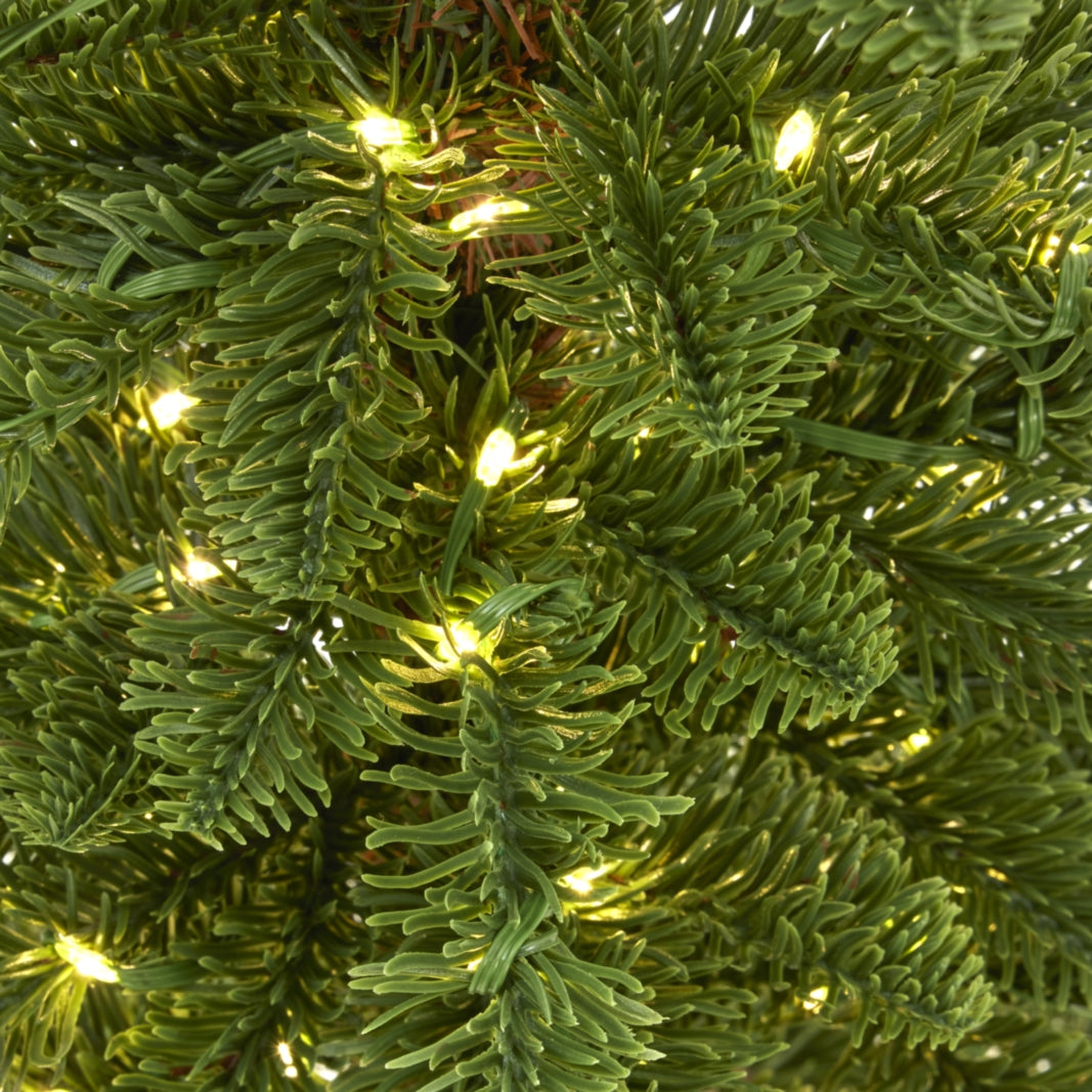 Close-up of green needle-like artificial foliage with warm lights and fine green wires running between the branches.
