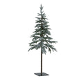 Full view of a snow-dusted green artificial tree with layered branches, an exposed brown lower trunk and a dark square base with four holes.