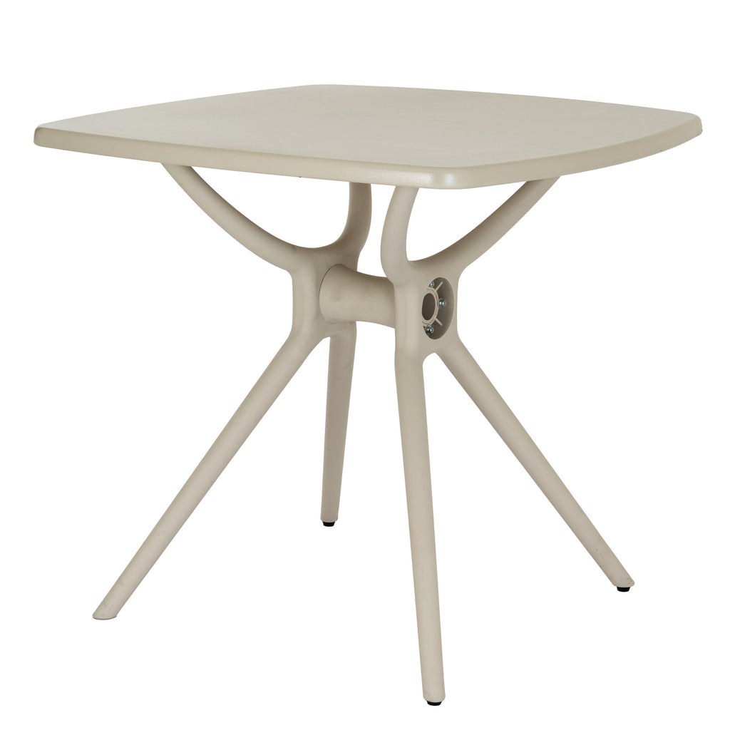 Three-quarter view of the putty-toned square dining table, showing the rounded tabletop corners and branching base with splayed legs.