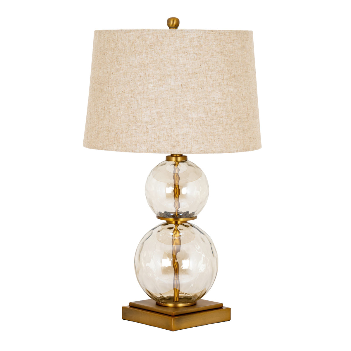 Table lamp with two stacked clear globes around a gold-coloured stem, a stepped square base and a tapered cream textured shade topped by a small finial.