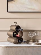 Wine rack holding three bottles on a pale sideboard beside two wine glasses on a round metallic tray.