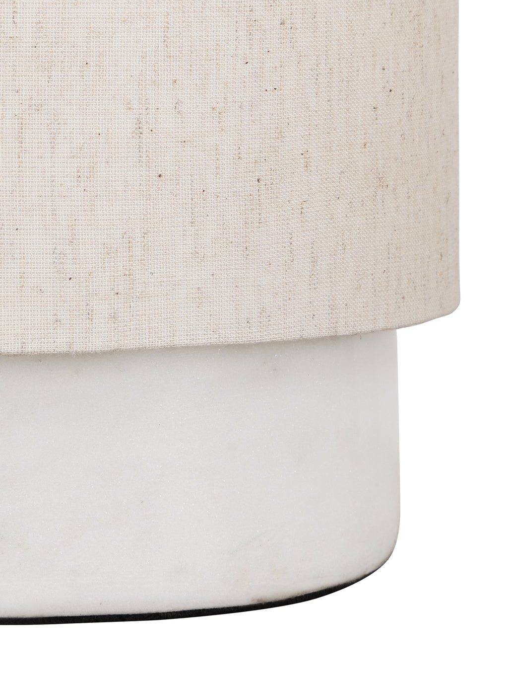 Angled close-up of the woven linen shade above the smooth white marble base and its rounded lower edge.