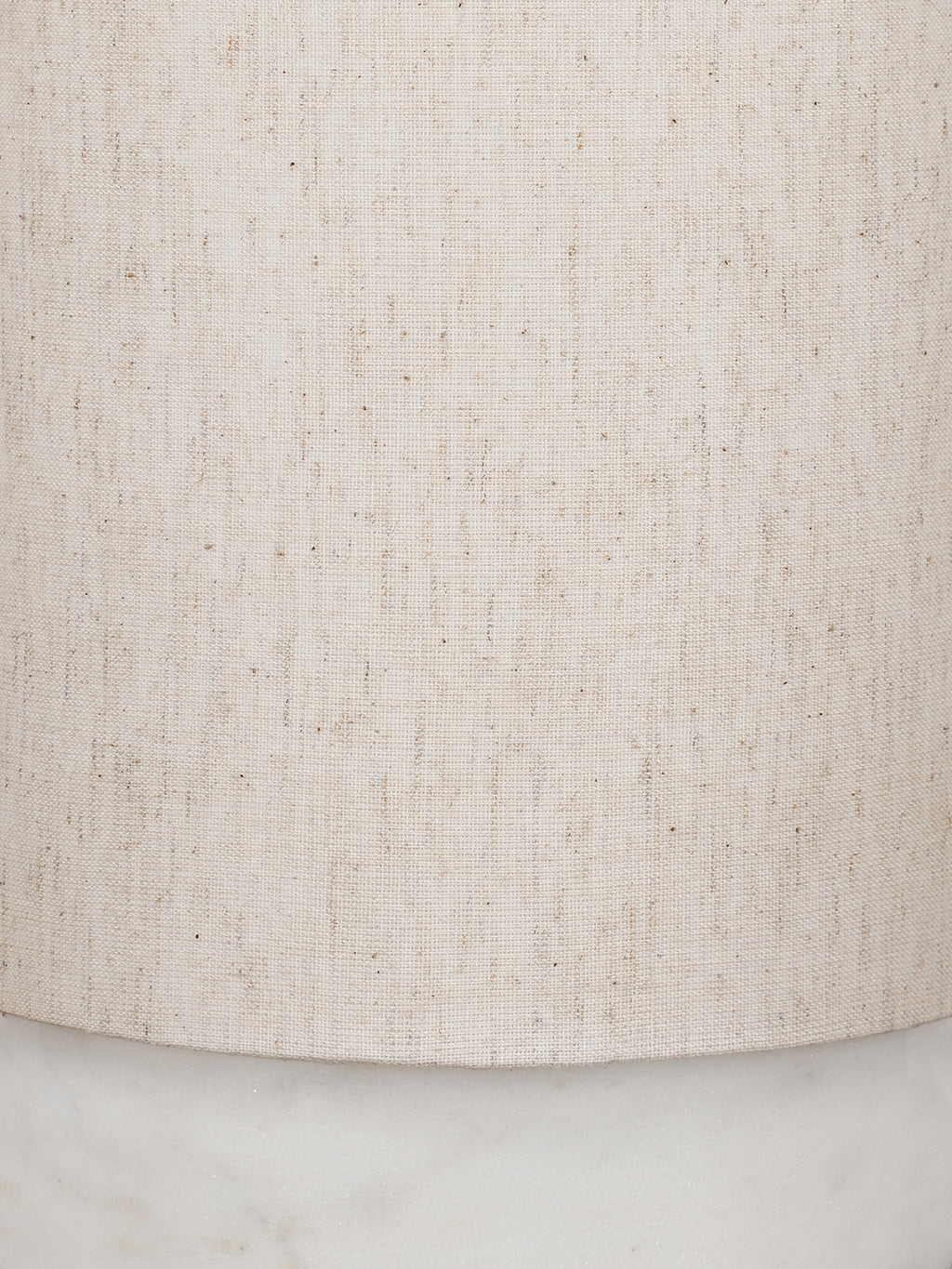 Close-up of the cream linen shade showing its weave and darker flecks, with part of the marble base below.