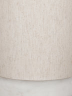 Close-up of the cream linen shade showing its weave and darker flecks, with part of the marble base below.
