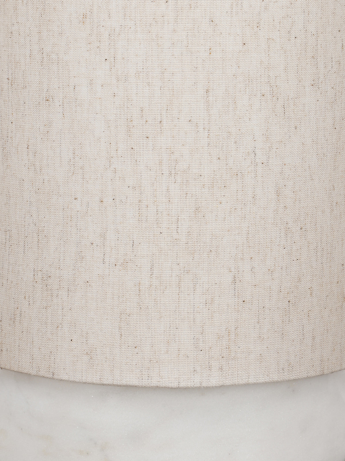 Close-up of the cream linen shade showing its weave and darker flecks, with part of the marble base below.