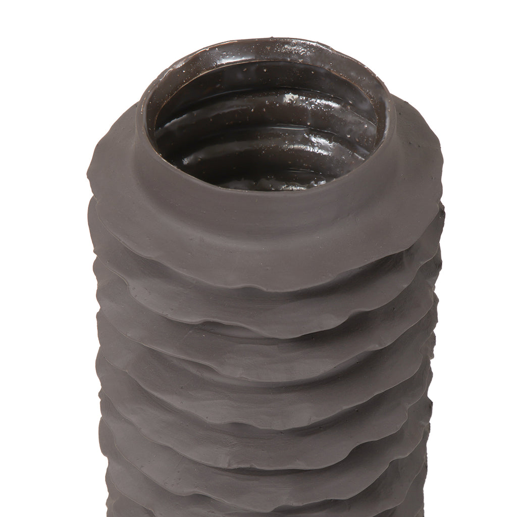 View into the vase opening, with a reflective dark interior above the matte ribbed exterior.