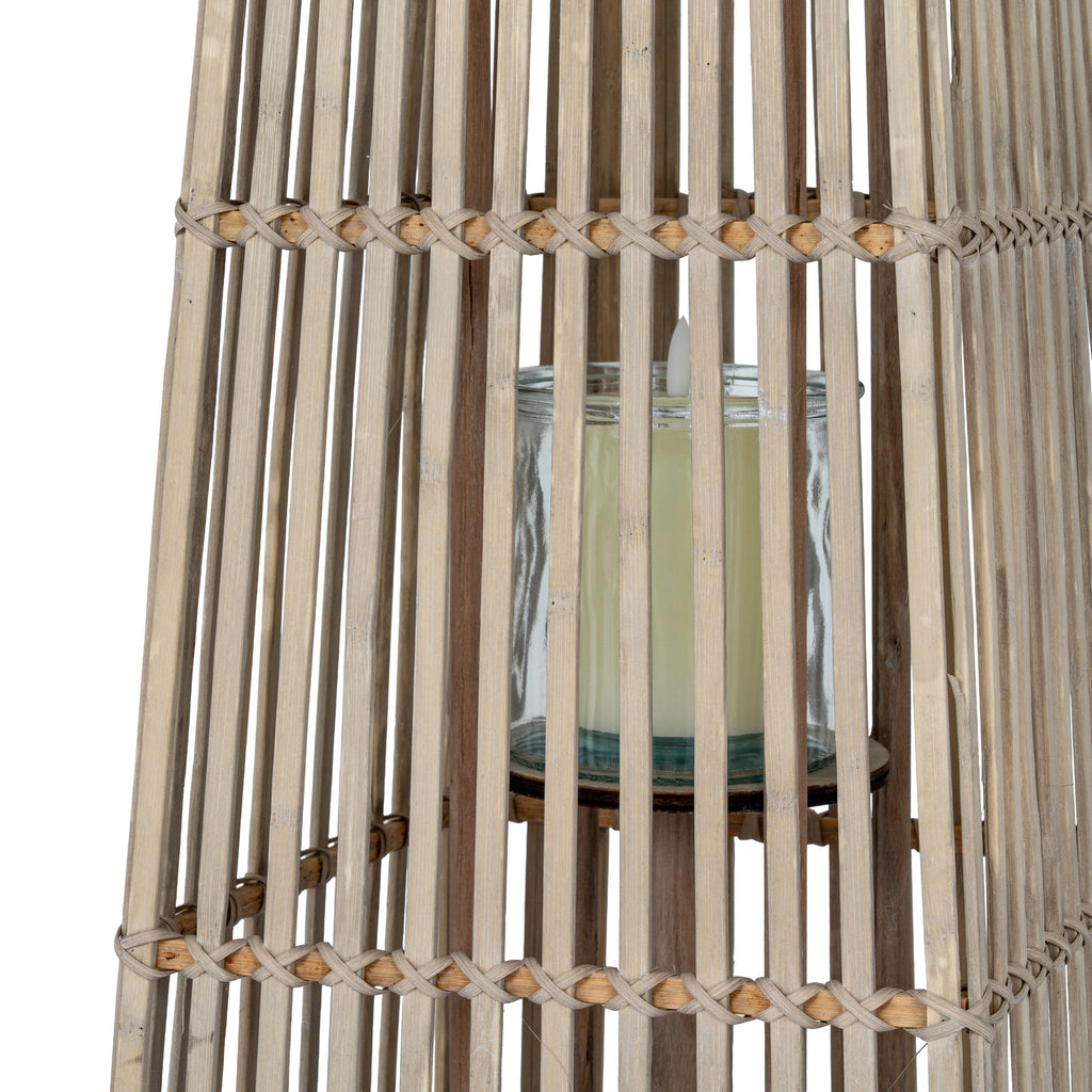 Close-up through the lantern's slats showing the transparent cylindrical holder, a pale candle and crossed bindings around the section joins.