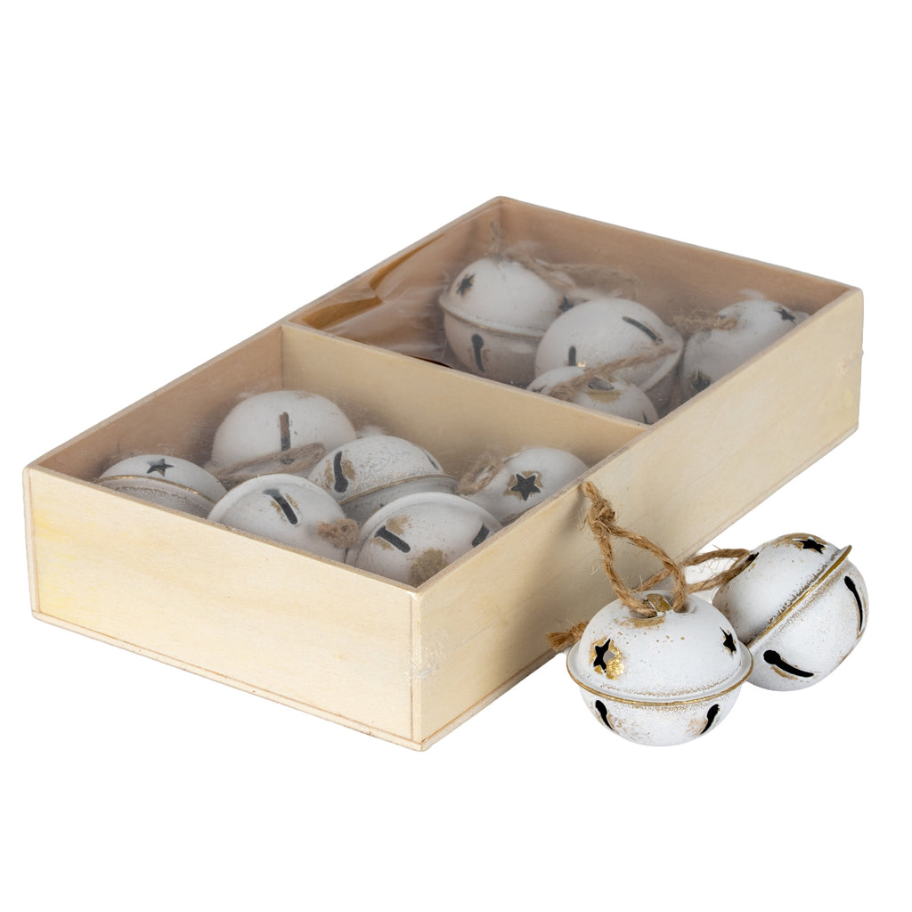 Angled view of cream-white bell ornaments in a divided pale-brown rectangular box, with two bells and their tan loops beside it.