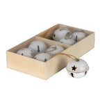 Angled view of white bell ornaments in a pale-brown divided box, with one bell outside showing a star opening, raised seam and tan loop.