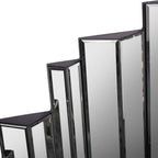 Detail of the mirror's stepped upper edge, showing adjacent bevelled panels and their angled faces.