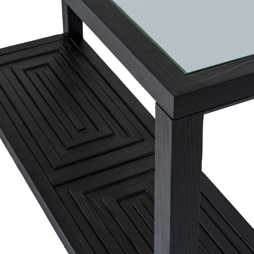 Angled close-up of the console table's reflective top corner and black square leg, with the raised geometric shelf pattern below.