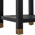 Close-up of a black table leg ending in a gold-toned section, with the patterned lower shelf behind it.