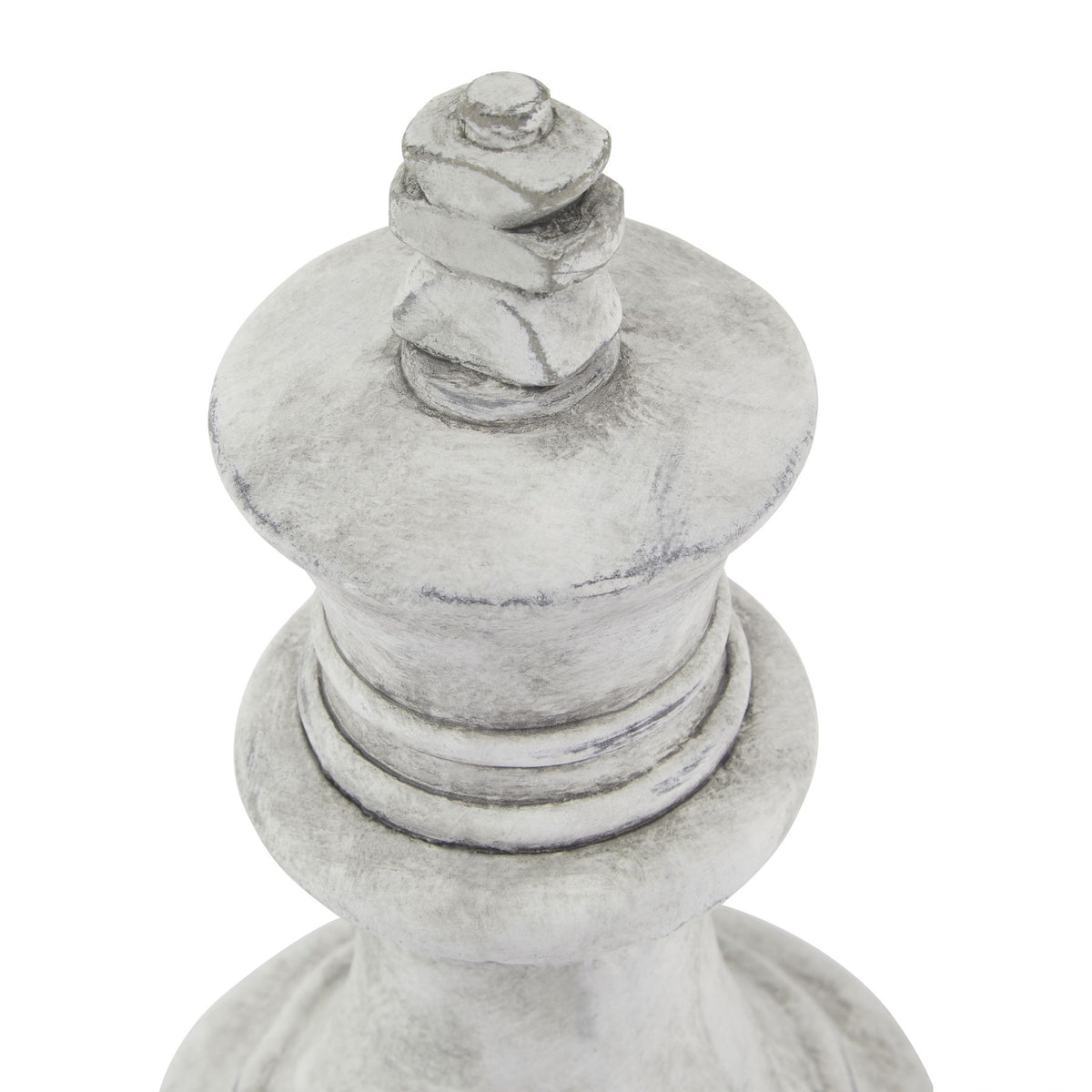 Angled close-up of the king ornament's stacked finial, broad crown and collar rings, showing darker weathered marks on the pale surface.