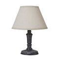 Table lamp with a wide tapered neutral shade, near-black shaped column and round foot against a white background.