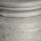 Close-up of the lamp base showing horizontal ridges, small pits and darker grooves across its pale finish.