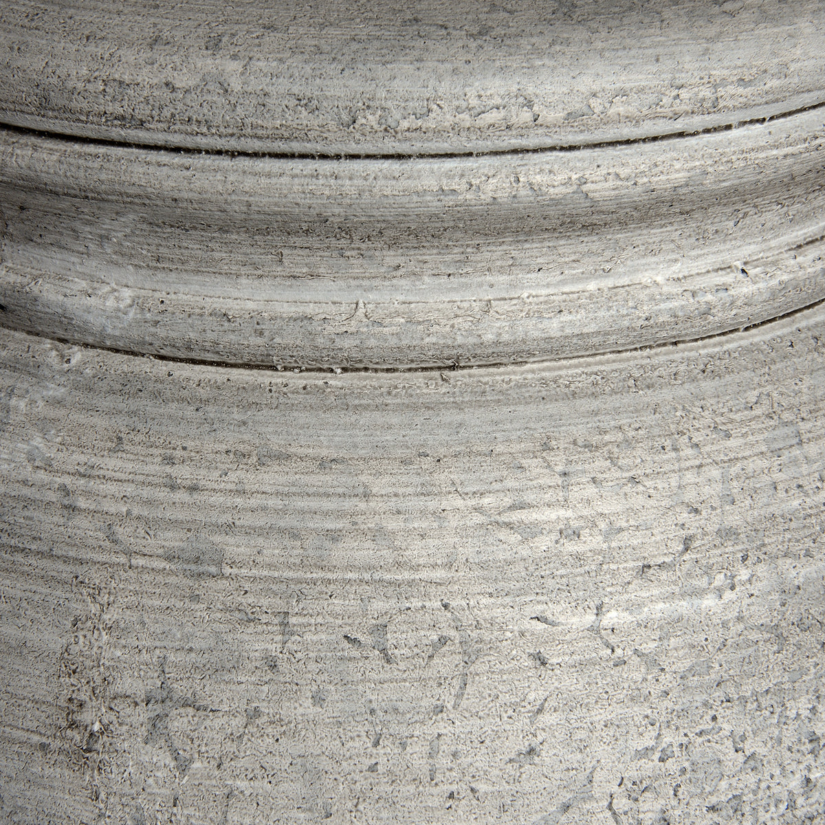 Close-up of the lamp base showing horizontal ridges, small pits and darker grooves across its pale finish.