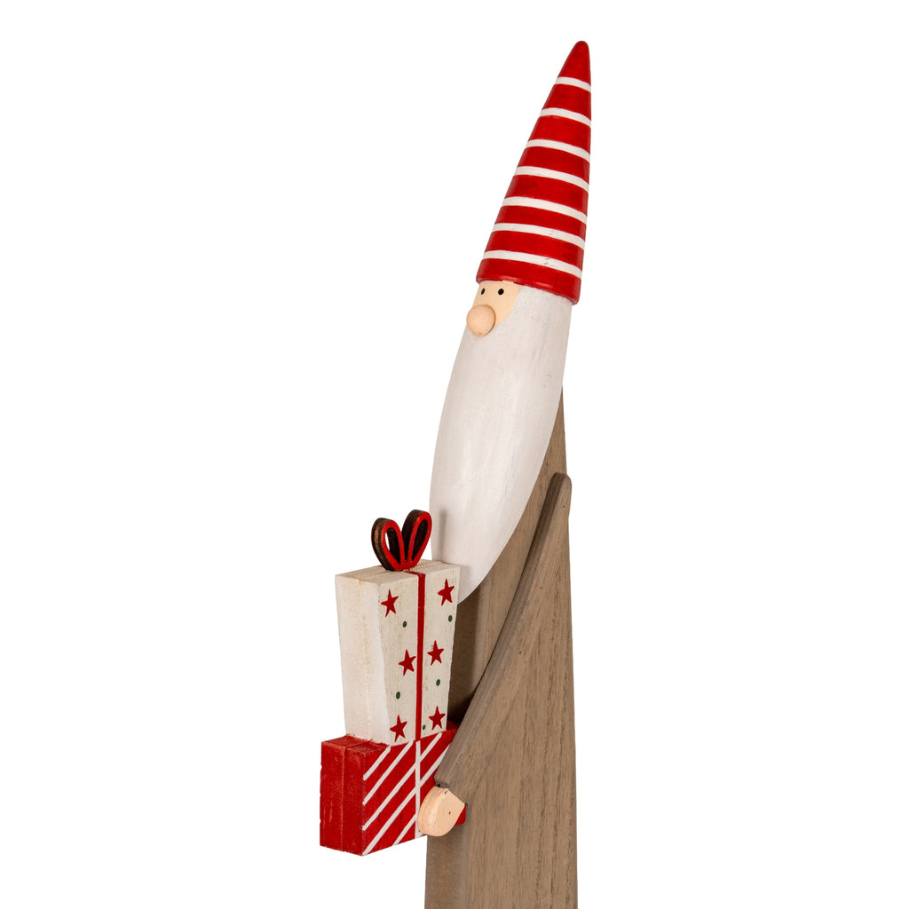 Close view of the elf’s striped red hat, round nose and white beard above presents decorated with stars, green dots and a looped bow.