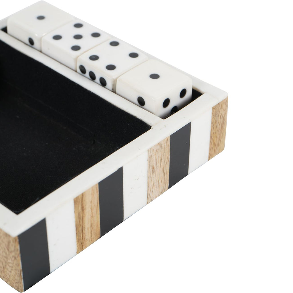 Close-up of white dice with black pips beside the tray's pale rim and alternating black, white and grain-patterned brown stripes.